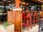 Lido Tall Outdoor Bar Stool - Charcoal & Red (Pictured in Restaurant Bar Setting)