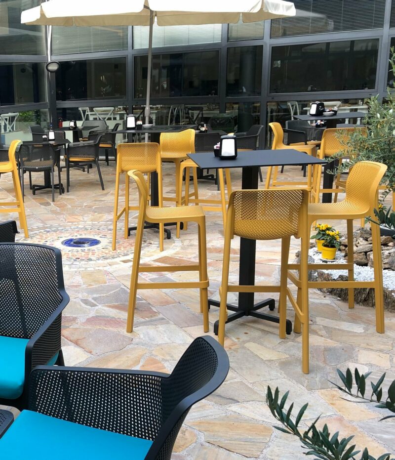NARDI Net Tall Bar Stools around Bar Leaner in an Outdoor Café Environment in Mustard Yellow