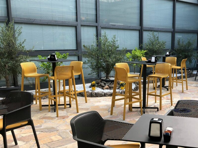NARDI Net Tall Bar Stools Outdoors at a Café in Mustard Yellow around Bar Leaners