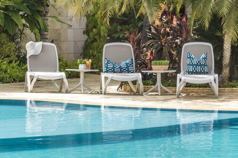 NARDI Omega Sun Loungers (White & Taupe) with Spritz Tables (White) next to Pool
